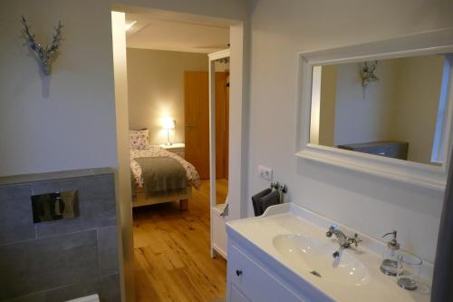 a bathroom with a sink and a mirror and a bed at Lax-á Asgardur Cottages in Selfoss