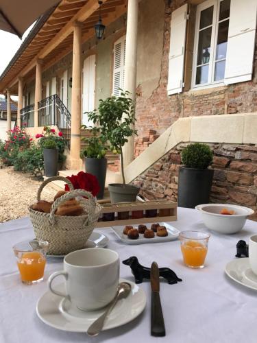 a table with cups and plates of food on it at Chambres d'hôtes Vers la Croix in Leynes