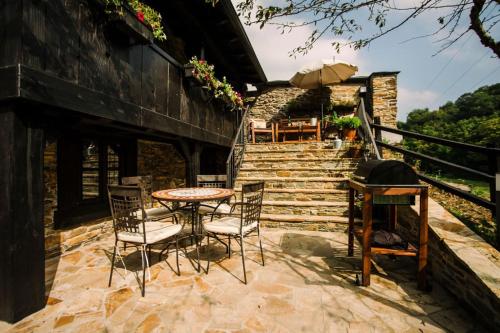 een patio met een tafel, stoelen en een trap bij Casa Calma Rural in Taramundi