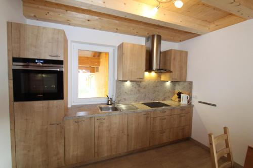 a kitchen with wooden cabinets and a window at Chalet Underhill in Kötschach