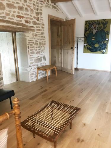 a living room with a table and a stone wall at Chambres d'hôtes Vers la Croix in Leynes