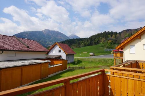 a wooden fence with houses and mountains in the background at Chalet Underhill in Kötschach