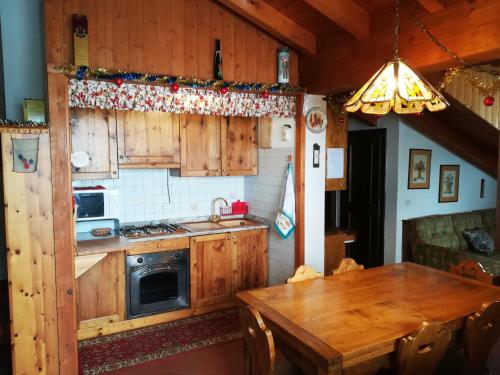 a kitchen with wooden cabinets and a wooden table at Appartamento Piancavallo in Piancavallo