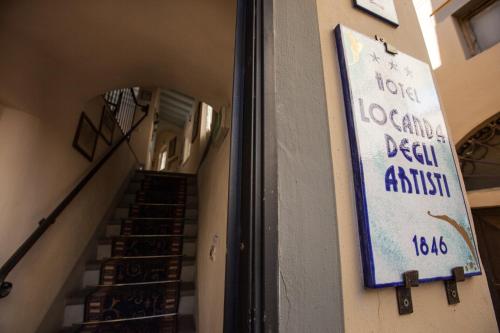 a sign on the side of a building with stairs at Hotel Locanda Degli Artisti in Borgo San Lorenzo