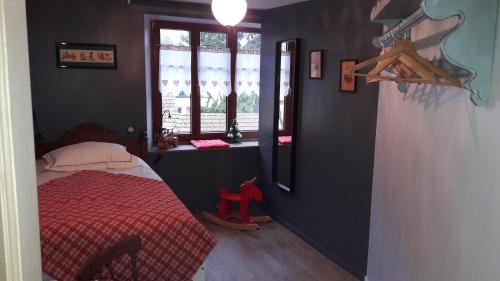 una camera con letto rosso e finestra di Au fil de l'écriture - Appartement sur la Route des Vins à riquewihr a Riquewihr
