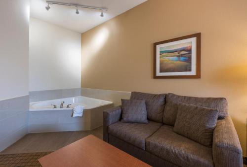 Quality Inn Airport في مونكتون: غرفة معيشة مع أريكة وحوض استحمام