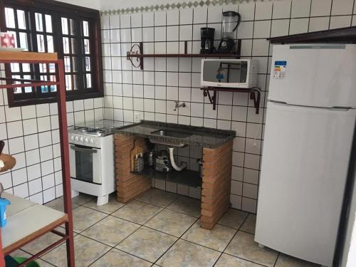 a kitchen with a white refrigerator and a stove at Residencial Albatroz in Caraguatatuba