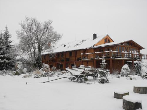 a large wooden house with snow on the ground at Farma Wenet in Broumov