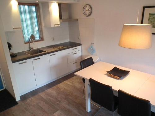 a kitchen with a table and chairs and a sink at Hollumerduinen in Hollum