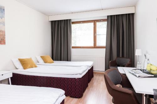 a hotel room with two beds and a table and chairs at Hotel Hermica in Tampere