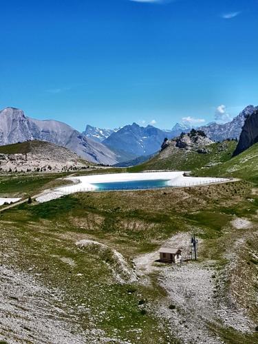 a lake in the middle of a field with mountains at Le p'tit Cozy in Le Dévoluy