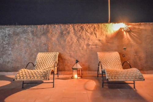 three chairs and a lamp in front of a wall at Dar nadia bendriss in Ouarzazate
