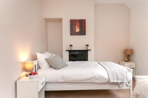 a bedroom with a white bed and a fireplace at Astley in Leicester