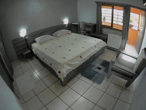 a bedroom with a large bed and a chair at Hotel Napoleon Lagune in Lomé