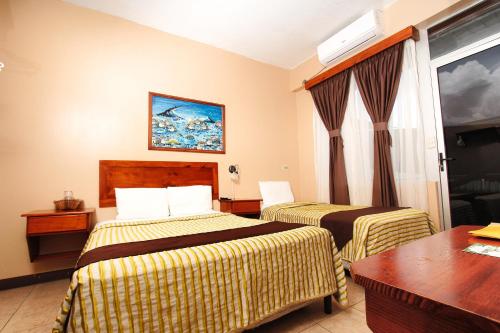 a hotel room with two beds and a table at Hotel Las Colinas in Fortuna