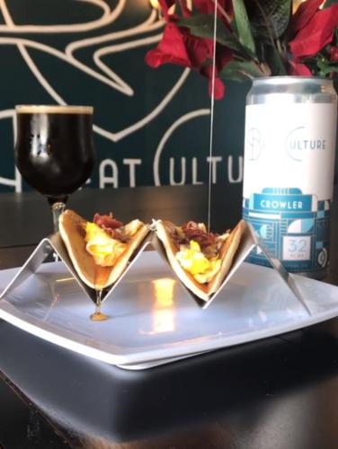 two tacos on a plate next to a glass of wine at enVision Hotel Miami International Airport in Miami
