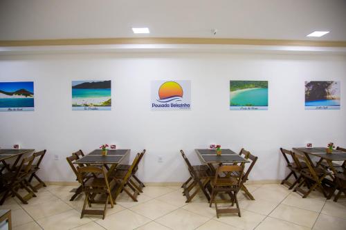 a dining room with tables and chairs and pictures on the wall at Pousada Belezinha in Arraial do Cabo