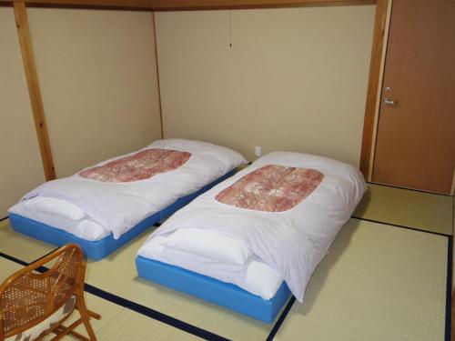 two beds in a small room with white sheets at Motomiya in Nakatsugawa