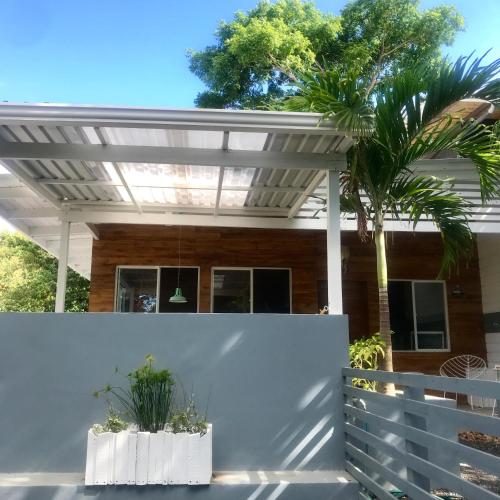 a white pergola over a white fence with two potted plants at Oleadas Maderas in San Juan del Sur
