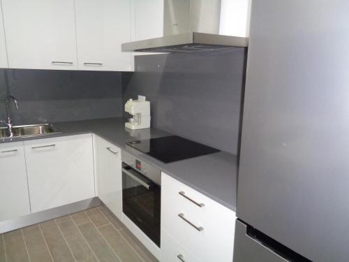 a kitchen with white cabinets and a stove top oven at Charrua do Mondego - Alojamento Local in Penacova