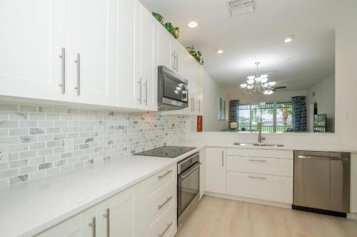 a kitchen with white cabinets and a sink at GreenLinks Golf View Villa Mustang at Lely Resort in Naples