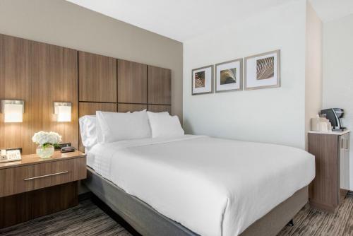 a bedroom with a large white bed and wooden cabinets at Holiday Inn Melbourne-Viera Conference Ctr by IHG in Melbourne