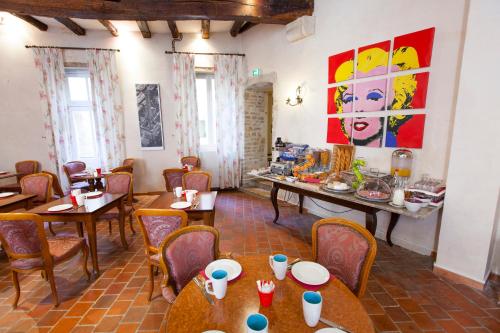 博恩的住宿－阿塔諾中心酒店，餐厅设有桌椅,墙上挂有绘画作品