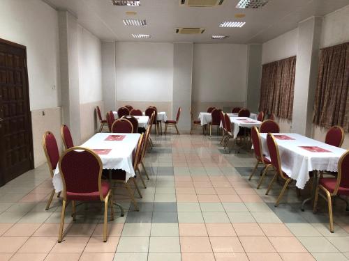 a dining room with white tables and red chairs at Maple Leaf Korean Hotel in Accra