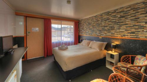 a bedroom with a bed and a brick wall at Queenstown Motor Lodge in Queenstown