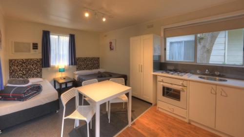 a small room with a bed and a table and a kitchen at Yarram Holiday Park in Yarram