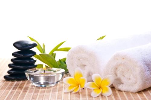 a spa room with towels and a candle and flowers at Ocean Terrace Suite And Spa Luxury in Nusa Penida