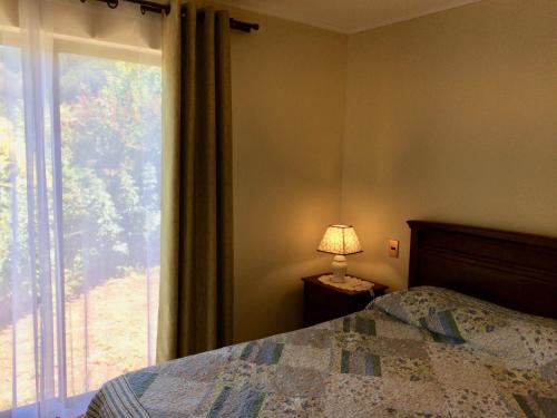 a bedroom with a bed and a window and a lamp at Casa confortable, campo y playa in Buchupureo