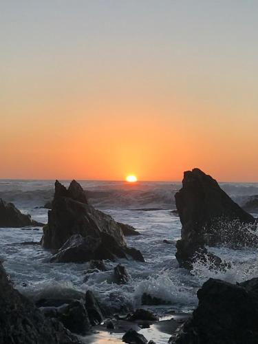 a sunset over the ocean with rocks in the water at Condominio Privado a Pasos del Mar in Pichilemu