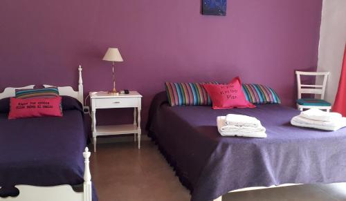 duas camas num quarto com paredes roxas em Habitación casa de campo. em São Rafael