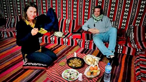 mężczyzna i kobieta siedzą na kanapie i jedzą jedzenie w obiekcie Dar rawi w mieście Taghit