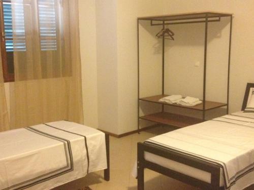 a hotel room with two beds and a mirror at Residencial Monte Cara in Mindelo