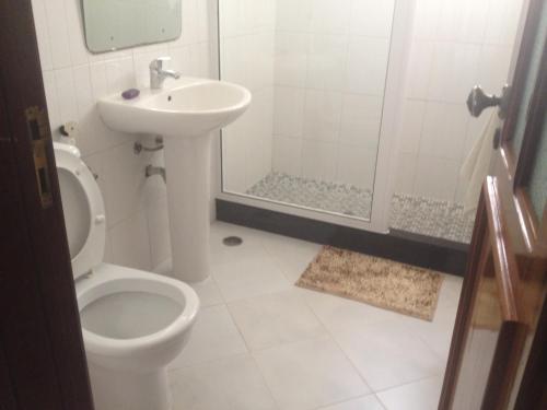 a bathroom with a toilet and a sink and a shower at Residencial Monte Cara in Mindelo