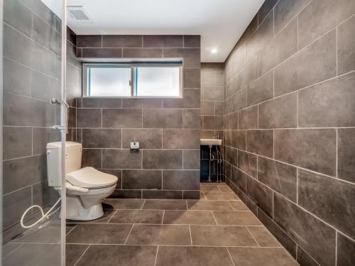 baño con aseo y paredes de azulejos en Apartments Madarao, en Iiyama