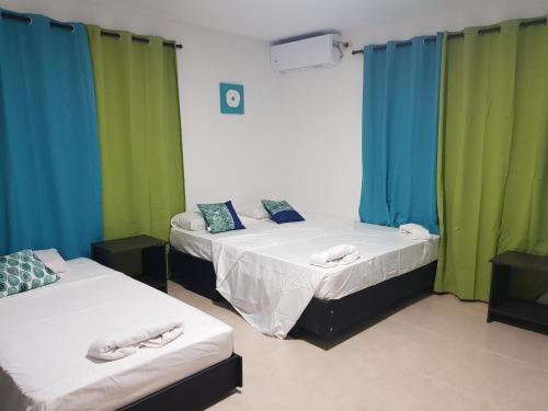 two beds in a room with green and blue curtains at Red Snapper Guest House in Providencia