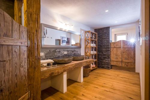 La salle de bains est pourvue de 2 lavabos et d'un mur en bois. dans l'établissement Luxus Ferienwohnung Almhütte, à Brixen im Thale