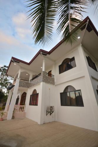 a white house with a palm tree in front of it at White Summerville Tourist Inn in Busuanga