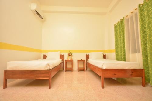 two beds in a room with green curtains at White Summerville Tourist Inn in Busuanga