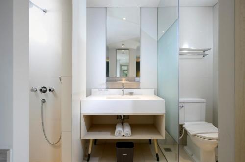 a white bathroom with a sink and a toilet at La Lisa Hotel Surabaya in Surabaya
