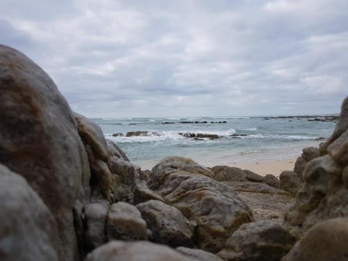a beach with some rocks and the ocean at Land's Edge Eco Friendly Cottages and Apartments in Struisbaai