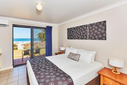 a bedroom with a bed and a view of the ocean at RAC Monkey Mia Dolphin Resort in Monkey Mia