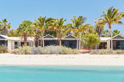 a row of houses on a beach with palm trees at RAC Monkey Mia Dolphin Resort in Monkey Mia