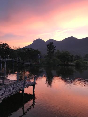 a bench sitting next to a lake at sunset at Numpu Baandin in Sam Roi Yot