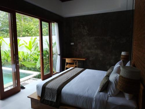 a bedroom with a bed and a large window at La Isla Villas Bali in Canggu