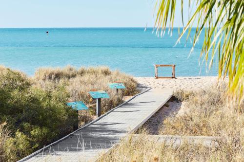a wooden pathway to the beach with the water at RAC Monkey Mia Dolphin Resort in Monkey Mia