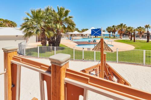 a fence with a view of a pool and palm trees at RAC Monkey Mia Dolphin Resort in Monkey Mia